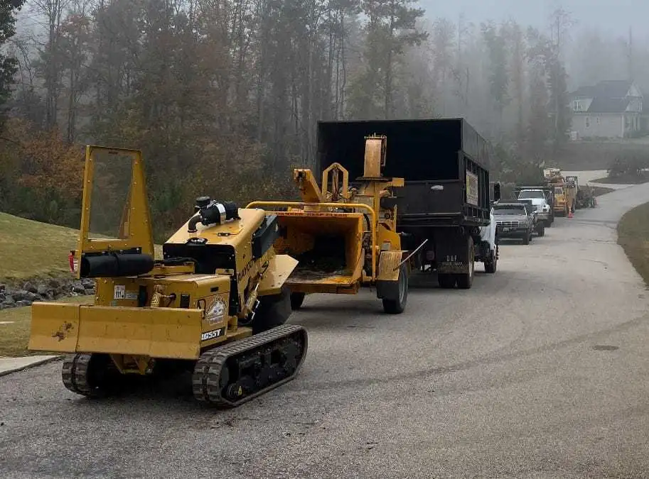 Fonvilletreeservice tracked stump grinder and wood chipper with dump trailer parked on residential street in NC during foggy morning