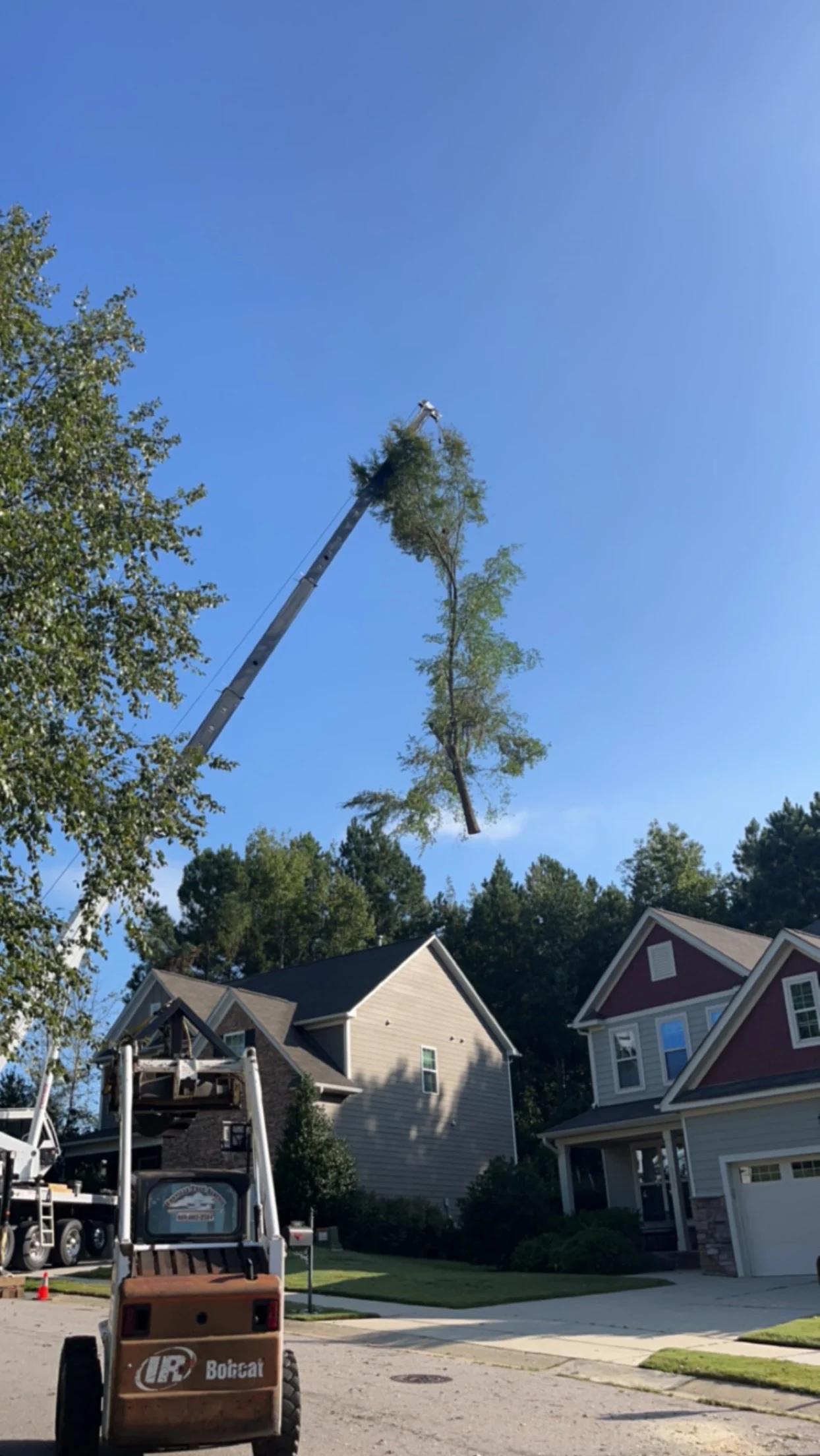 Fonvilletreeservice crane lifting tall tree section above residential homes during professional tree removal in Rolesville, NC
