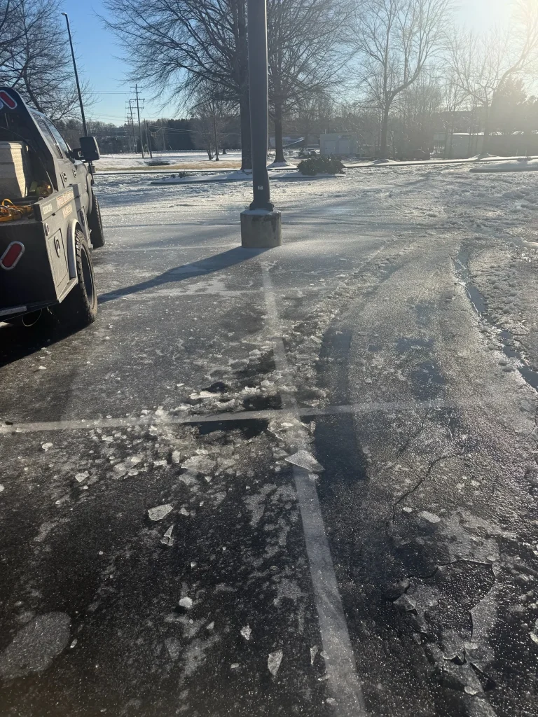 Fonvilletreeservice service truck parked near broken ice sheets scattered across commercial parking lot surface during winter in NC.